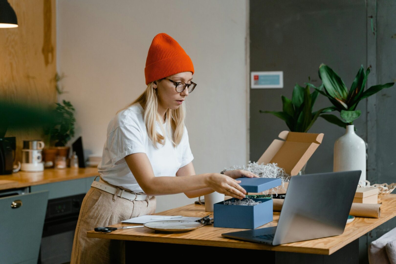 A woman in an orange hat is working on her laptop.